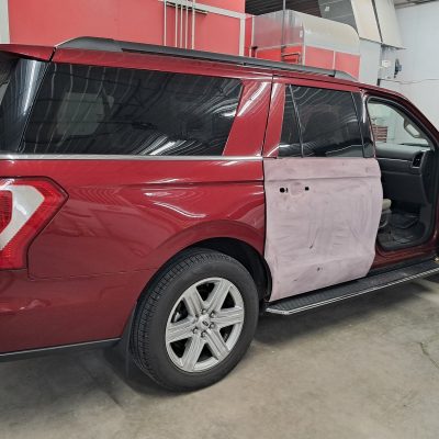 Repair and painting of the back passenger door on a red SUV