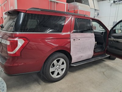 Repair and painting of the back passenger door on a red SUV