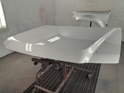 Newly repaired and painted auto body parts including hood of vehicle