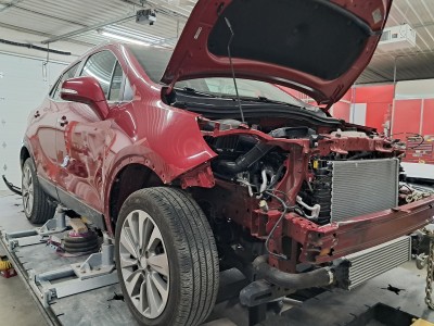 Major collision repair work on red vehicle up on a lift